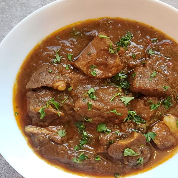 Rangeen Kitchen's Indian lamb curry, a rich brown stew with tender meat pieces and fresh cilantro.