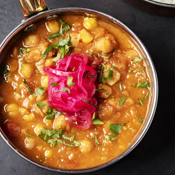 Rangeen Kitchen's Chana Masala, a chickpea curry, garnished with fresh cilantro and pickled red onions.